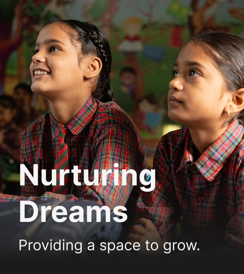 Two schoolgirls in plaid uniforms sitting in a colorful classroom with an overlaid Text “Nurturing Dreams – Providing a space to grow".