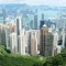 hongkong Tall buildings and skyscrapers seen from a green hilltop with water and more city buildings in the background.